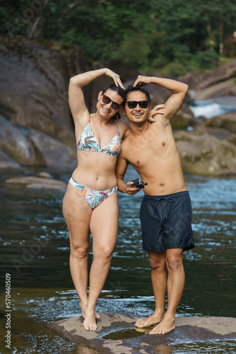 multi racial couple enjoying a day at the river doing a heart with hands