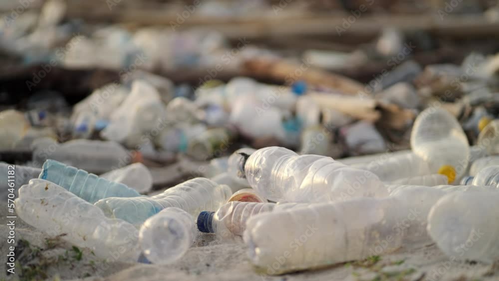 Slow across polluted beach with plastic bottles.  Plastic in ocean and ocean trash close up view