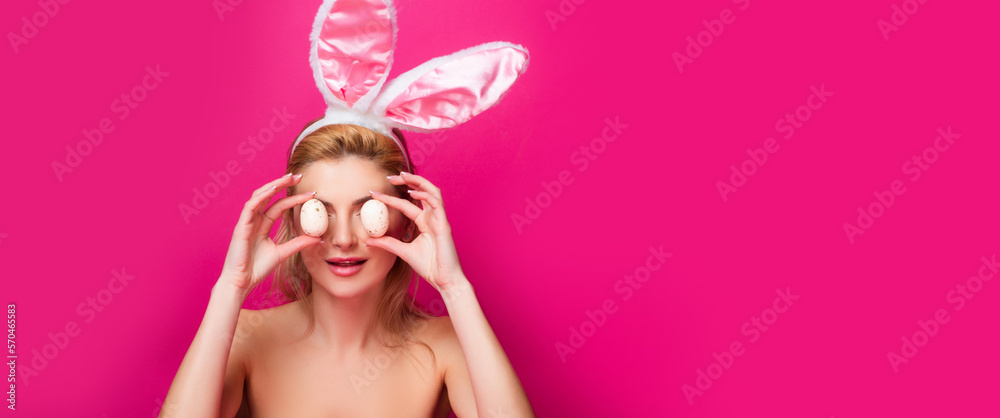 Lovely woman in rabbit costume. Beautiful girl with rabbit ears and easter eggs on pink background. Horizontal photo banner for website header design.