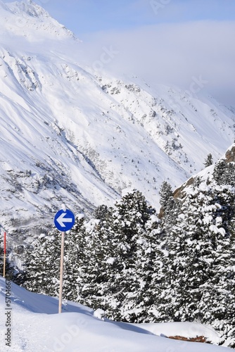 Blue piste sign backdropped by a beautiful snowy mountain and snowy trees in Obergurgl Ski Resort, Tyrol, Austria