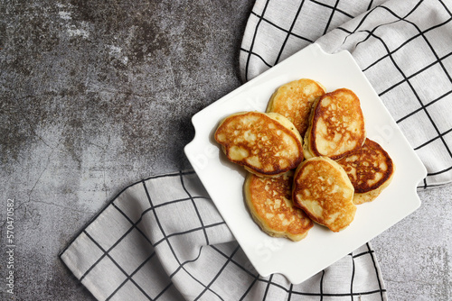 Cottage cheese pancakes on a white square  plate on a dark background. Top view, flat lay