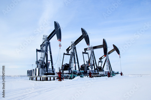 Winter in the oilfield cowered with white snow with black pumpjacks. photo