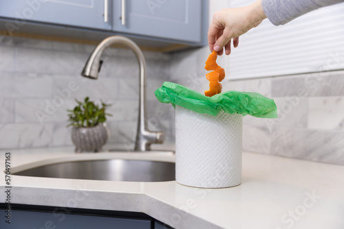 Woman putting food in the compost bin in the kitchen