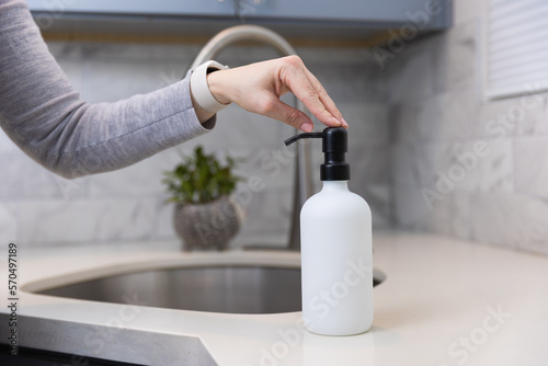 Woman refilling the soap dispencer with a funnel photo