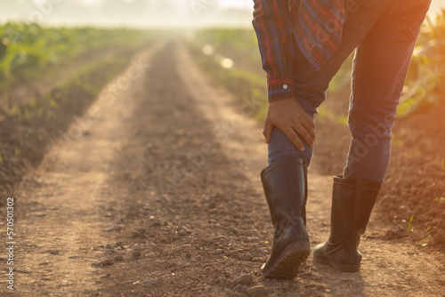 Injuries or Illnesses, that can happen to farmers while working. Man is using his hand to cover over Calf because of hurt, pain or feeling ill.