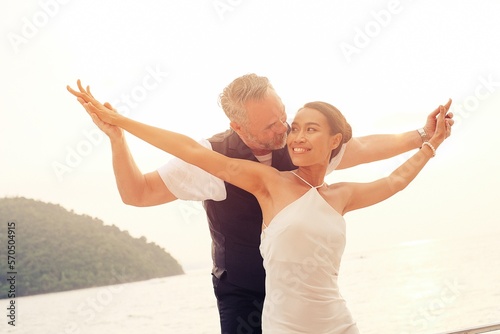Happy life retirement plan concept, Senior business man and his wife freedom dancing celebration event on the yacht deck over romance sunset sky, ocean view scene, marriage anniversary luxury summer