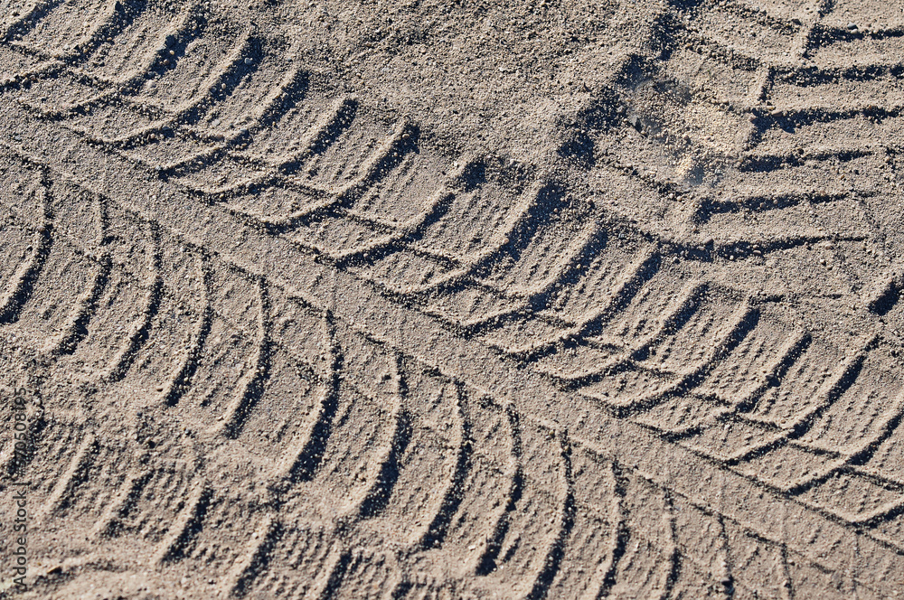 Tire tracks in the sand on a sunny day. Texture on dry dusty surface.