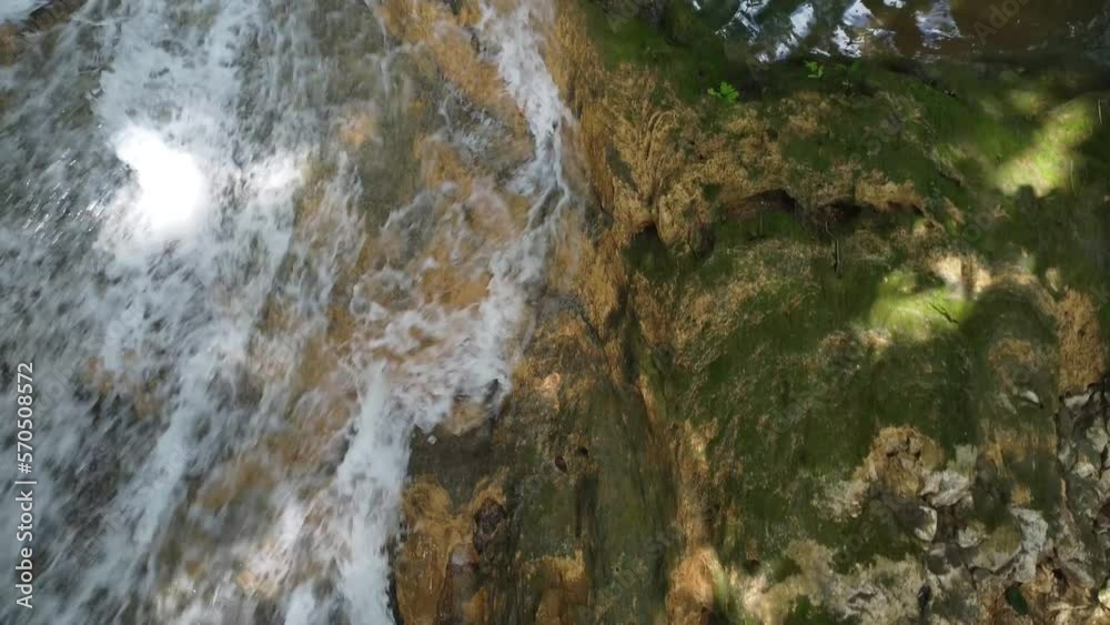 Drone shot of a water flowing from the rocks inside the jungle, waterfall, cristal water, nature spot Drone shot of a water flowing from the rocks inside the jungle, waterfall, cristal water, nature spot