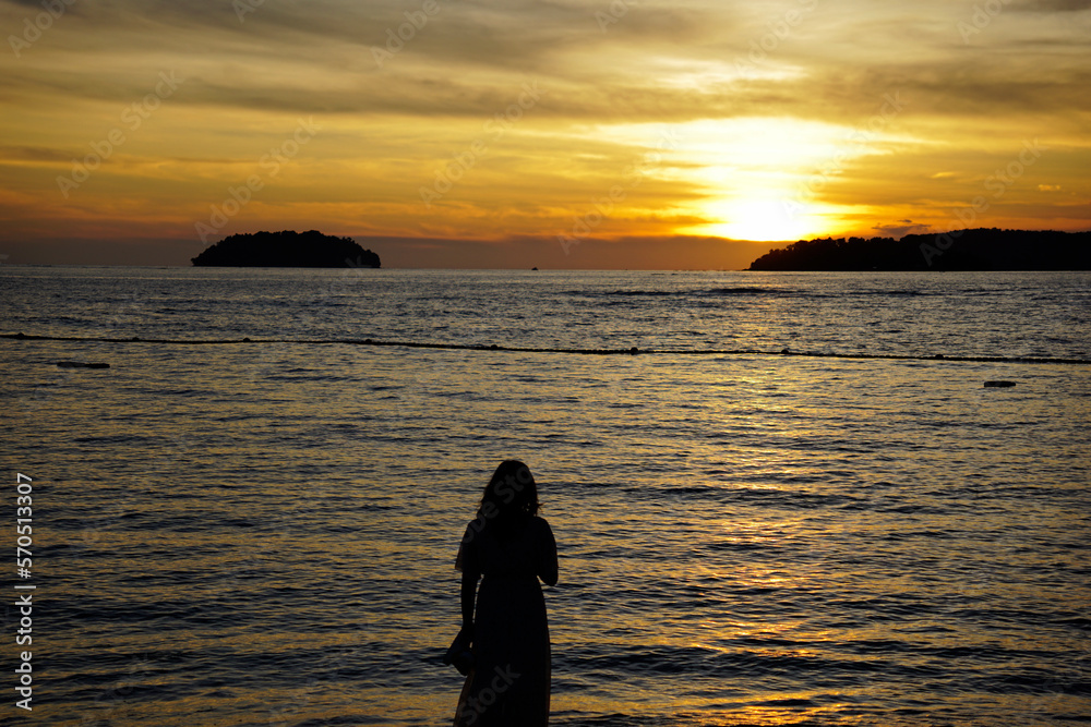 Silhouette of a woman watching sunset on the shore on Kinabalu Island, Malaysia Silhouette of a woman watching sunset on the shore on Kinabalu Island, Malaysia