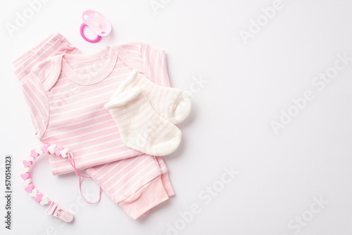 Baby shower concept. Top view photo of pink shirt pants socks pacifier and teether chain on isolated white background with copyspace