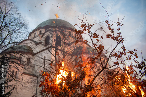 People watch a ceremonial burning of dried oak branches - the Yule log symbol for the Orthodox Christmas Eve in front of St. Sava church on January 6, 2023 in Belgrade, Serbia.
