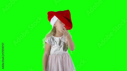 Playful 5 years old girl child playing with Christmas Santa hat. Chroma key green screen background