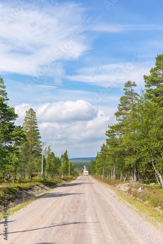 Gravel road with a caravan on a straight line in the woods © Lars Johansson
