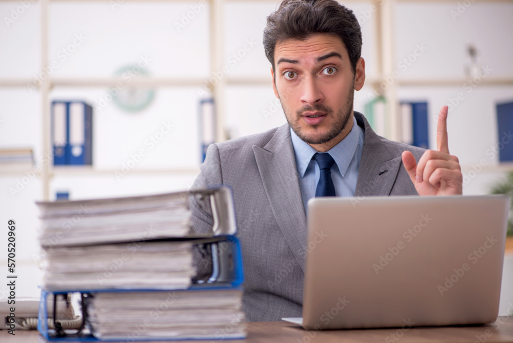 Young male employee and too much work in the office Young male employee and too much work in the office