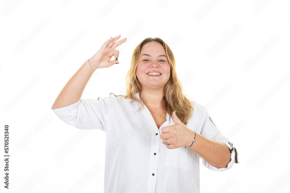 Happy smiling young business woman with fingers okay gesture showing thumb up palm sign on white background Happy smiling young business woman with fingers okay gesture showing thumb up palm sign on white background