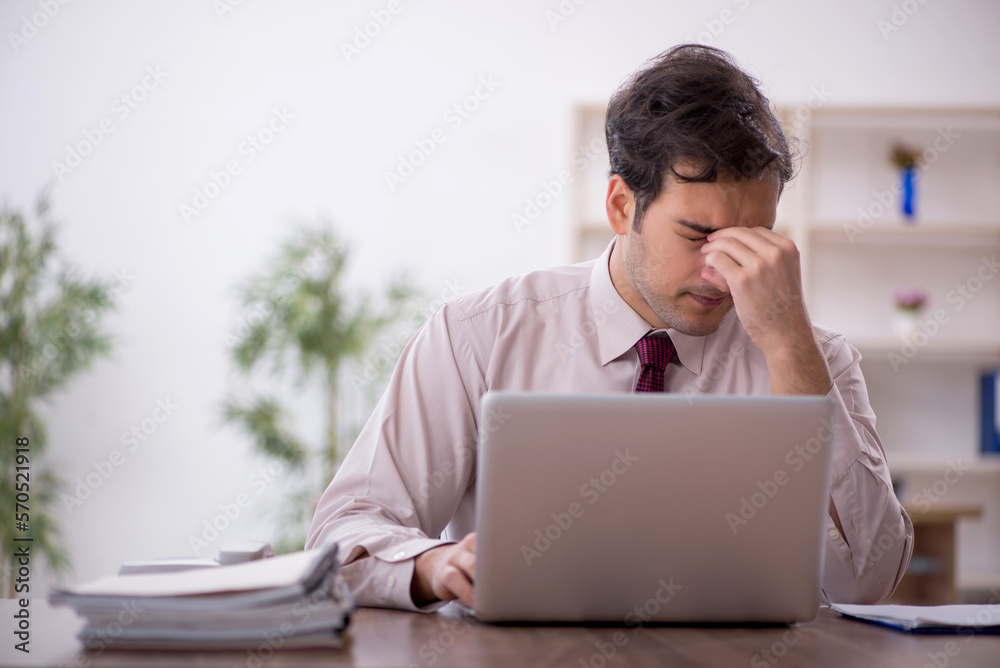 Young male employee and too much work in the office Young male employee and too much work in the office