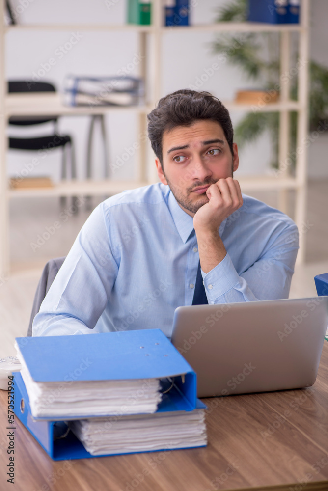 Young male employee and too much work in the office Young male employee and too much work in the office