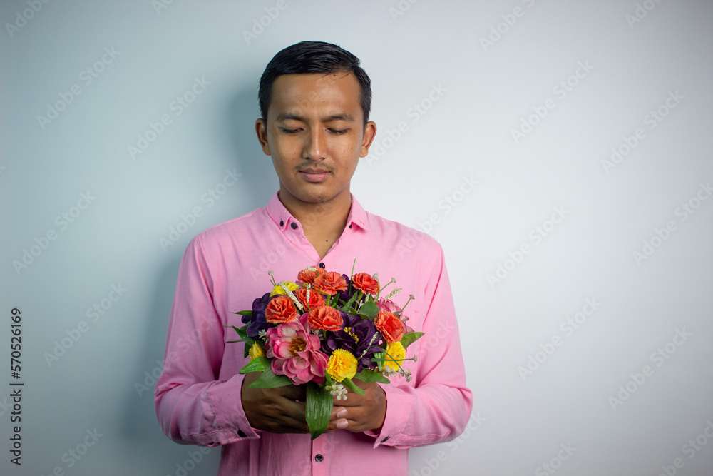 Portrait of Asian young man holding flower wearing pink shirt isolated on white background. Portrait of Asian young man holding flower wearing pink shirt isolated on white background.