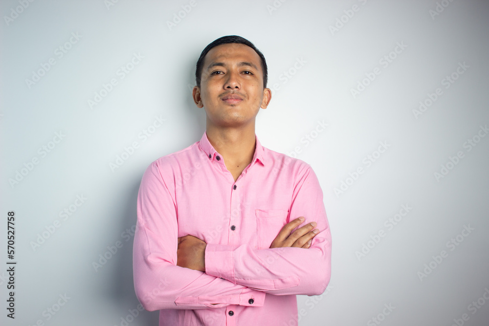 Portrait of confident smiling Asian young man wearing pink shirt standing with arms folded isolated on white background. Portrait of confident smiling Asian young man wearing pink shirt standing with arms folded isolated on white background.