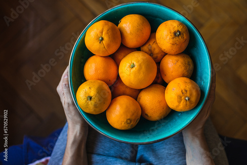 A mother and son place organic oranges in a green bowl. photo