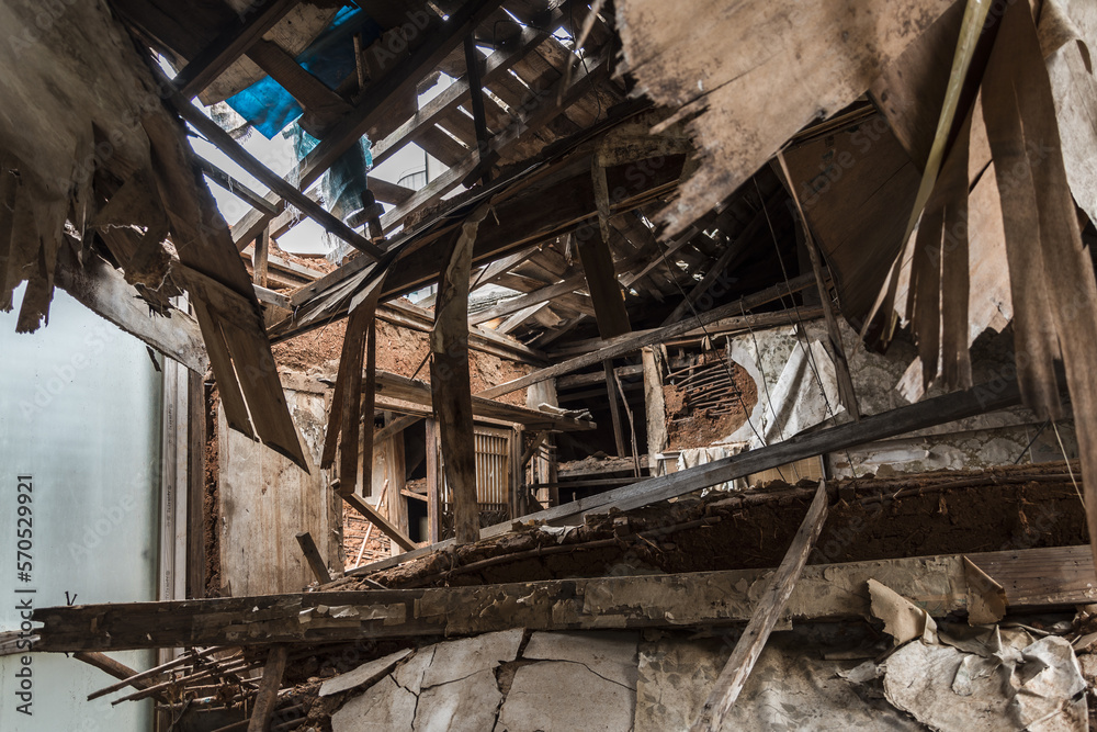 Urbex, destroyed room of an abandoned traditional South-Korean house, the walls, door and windows are broken, the roof collapsed, there are remains on the floor, the room is messy, dirty and dusty