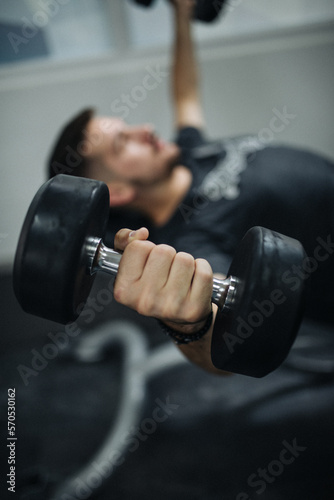 Close-up image young man lifting weights in a gym. photo