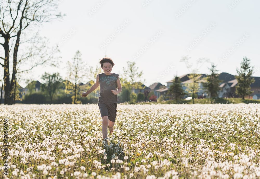 Boy running in a grassy field full of dandelions on summer day. Boy running in a grassy field full of dandelions on summer day.