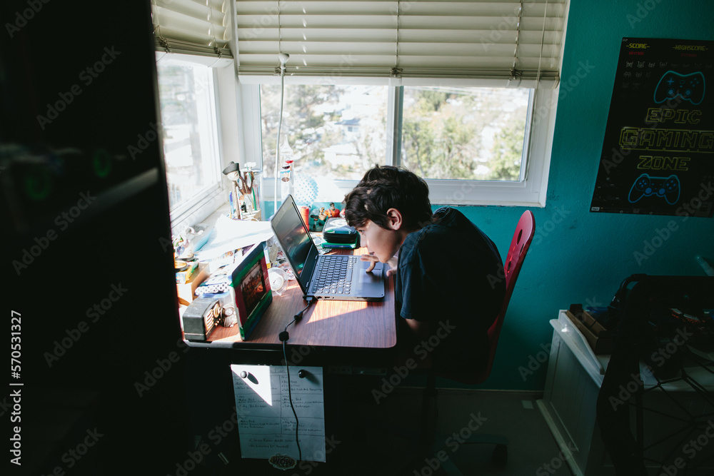 Ten year old boy working on a laptop for school during quarantine Ten year old boy working on a laptop for school during quarantine