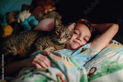 Boy and his tabby cat snuggle cheek to cheek in bed