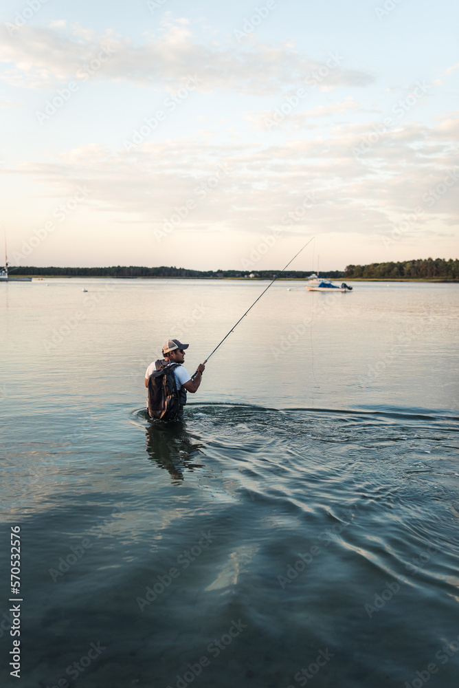 Hispanic man fly fishing in ocean off beach in afternoon Hispanic man fly fishing in ocean off beach in afternoon