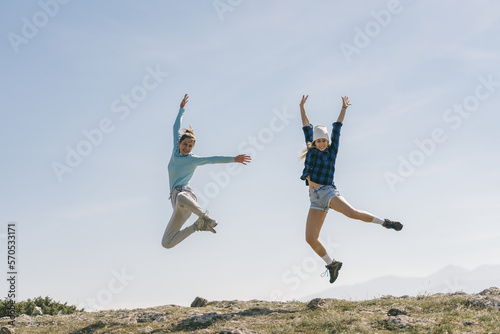 A front view photo of two girls jumping from luck