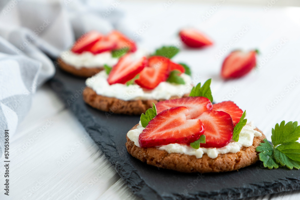 Healthy toast with strawberry, cream cheese and mint leaf. Tasty breakfast. Clean eating, dieting or recipe of healthy snack sandwich for vegetarian. Restaurant serving on slate board.