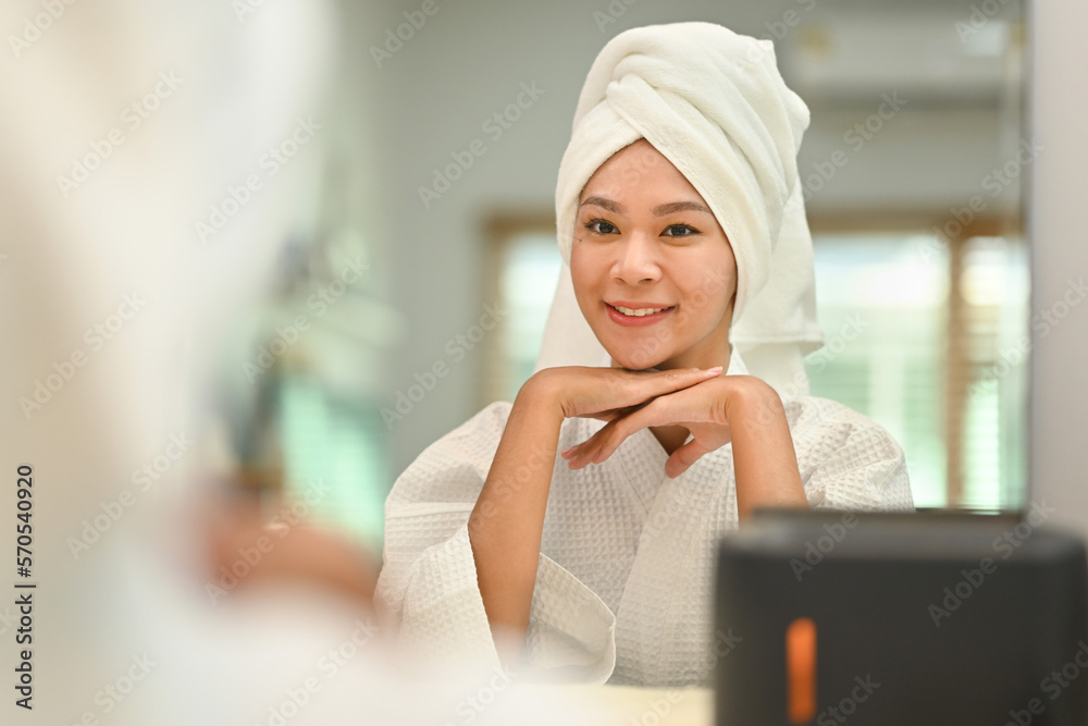 Serene young woman in bathrobe and towel on head relaxing after taking shower bath. Beauty treatment concept Serene young woman in bathrobe and towel on head relaxing after taking shower bath. Beauty treatment concept