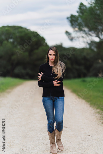 Chica joven con pelo largo liso y vestidos pintorescos en zona boscosa tomándose fotos y posando