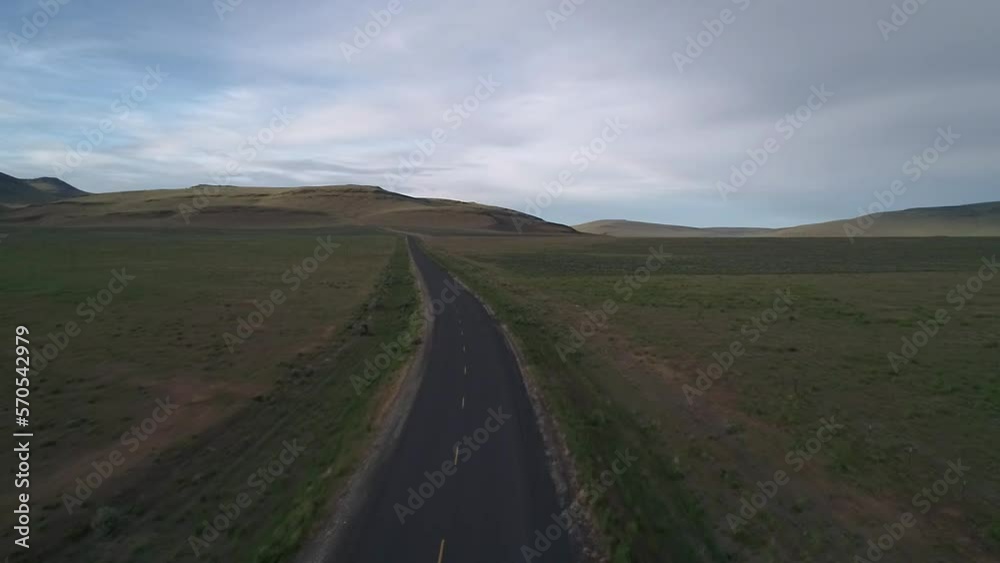 Handheld shot of road amidst landscape against cloudy sky at Alvord Desert Handheld shot of road amidst landscape against cloudy sky at Alvord Desert