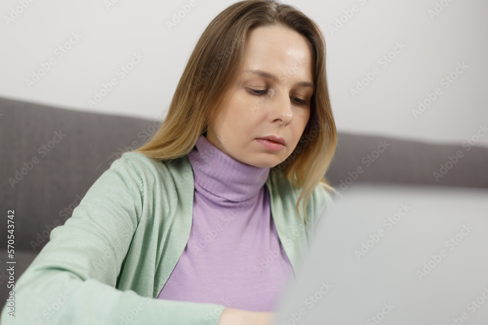 Focused white woman working on computer at home. Serious adult female person doing distant work online Focused white woman working on computer at home. Serious adult female person doing distant work online