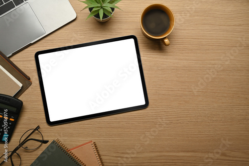 Digital tablet with empty screen, eyeglasses, notebook and coffee cup on wooden table