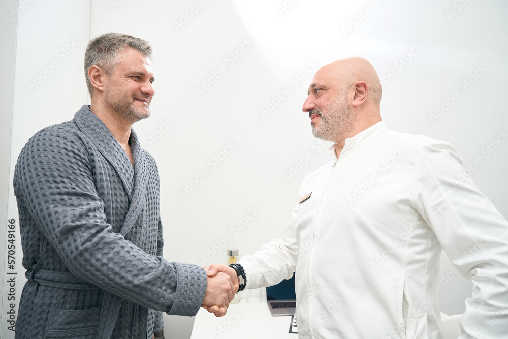 Handsome patient is shaking hand of the doctor in medicine center Handsome patient is shaking hand of the doctor in medicine center