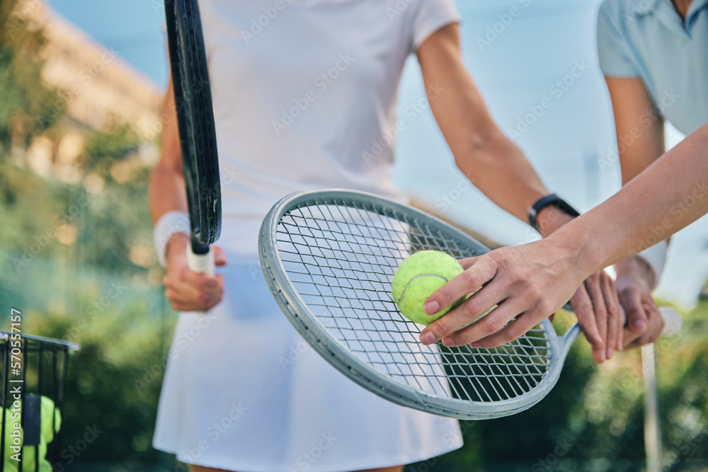 Tennis training, hands and ball with women and athlete on outdoor turf, instructor or coach, fitness motivation and help. Exercise, sports lesson and workout together, teaching and learn on court