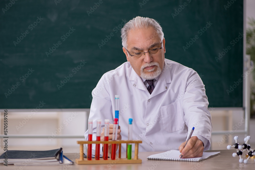 Old male chemistry teacher in the classroom Old male chemistry teacher in the classroom