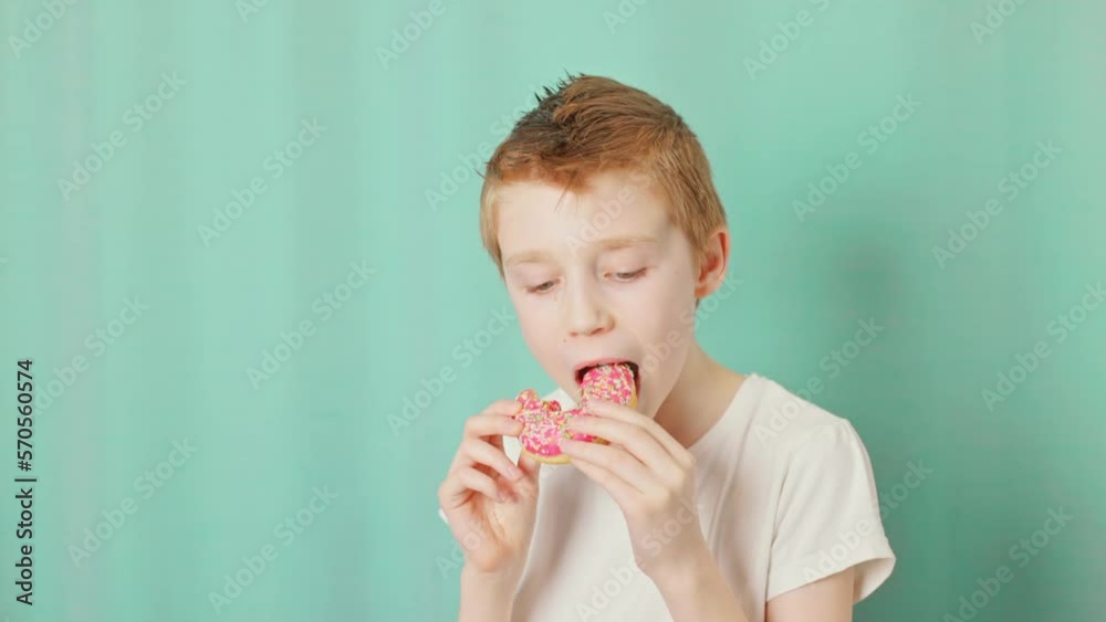 Boy bites off doughnut and makes surprised eyes in a National doughnut day. Slow motion video. Boy bites off doughnut and makes surprised eyes in a National doughnut day. Slow motion video.