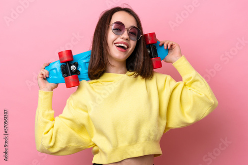 Young Ukrainian woman isolated on pink background with a skate