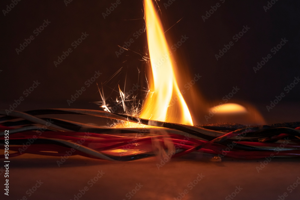 Electric wires are burning on a dark background. A short circuit in the wires., the cause of the