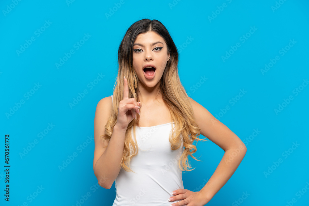 Young Russian girl isolated on blue background thinking an idea pointing the finger up