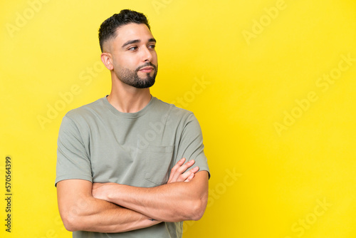 Young Arab handsome man isolated on yellow background looking to the side