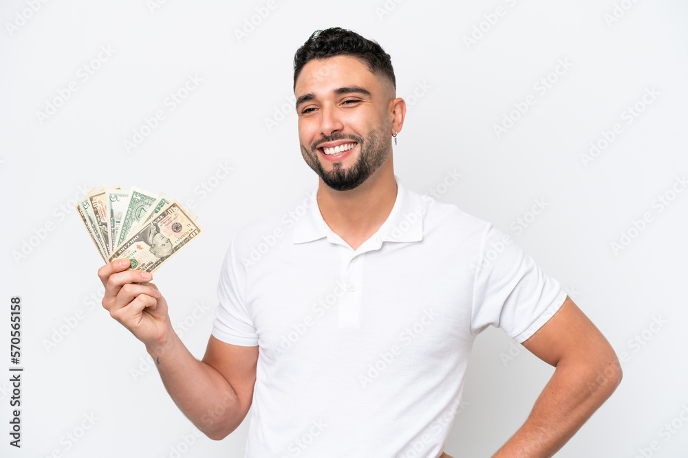 Young Arab man taking a lot of money isolated on white background posing with arms at hip and smiling Young Arab man taking a lot of money isolated on white background posing with arms at hip and smiling