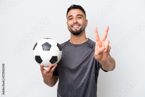 Arab young football player man isolated on white background smiling and showing victory sign