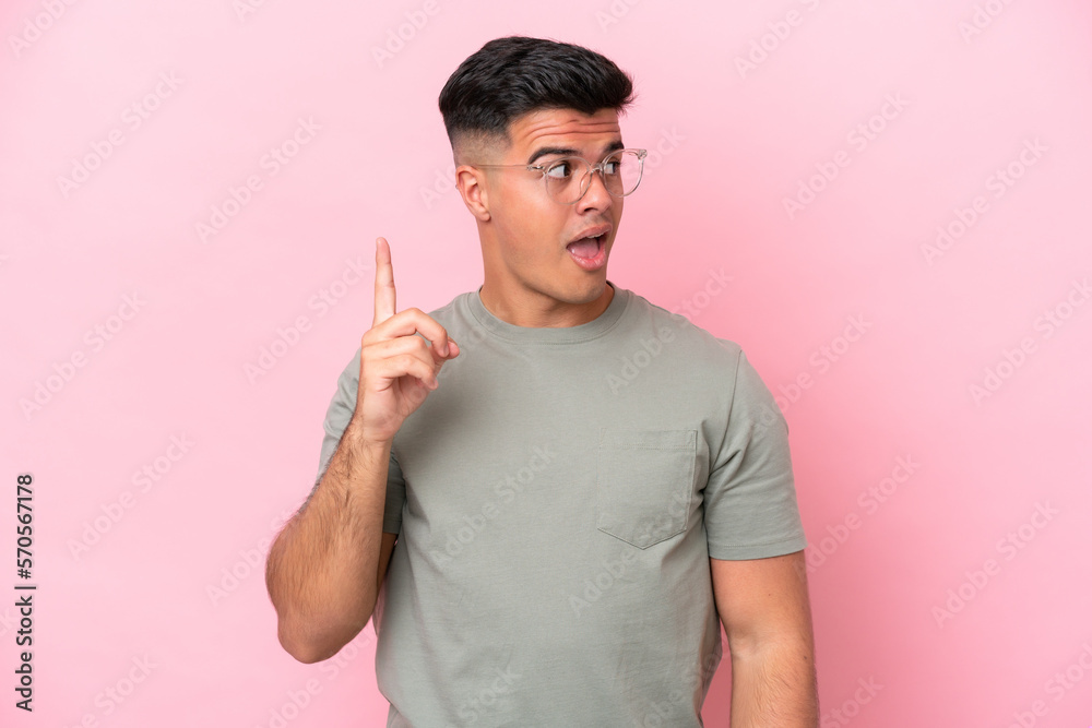 Young caucasian handsome man isolated on pink background intending to realizes the solution while lifting a finger up