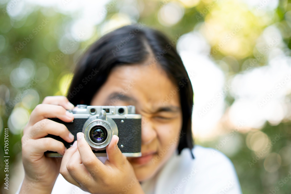 woman taking a picture with a camera, film camera in the hands of a girl taking a picture. Green trees bokeh background, woman taking a photo with a camera, selective focus, soft focus. woman taking a picture with a camera, film camera in the hands of a girl taking a picture. Green trees bokeh background, woman taking a photo with a camera, selective focus, soft focus.