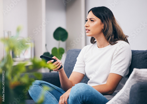 фотографія Woman confused, watching tv and remote control, relax at home and squint with vision problem and streaming movie